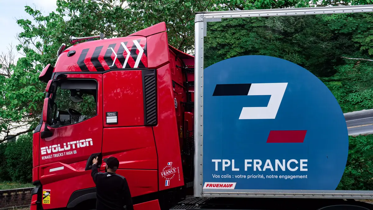 Tracteur rouge TPL France attelé à une remorque au logo de l’entreprise