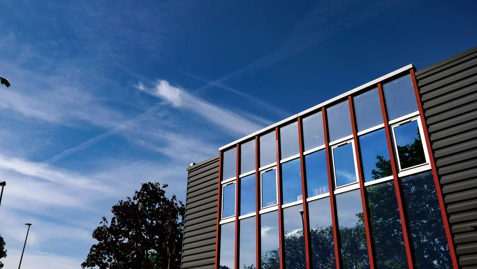 Façade vitrée des locaux de TPL France sous un ciel bleu